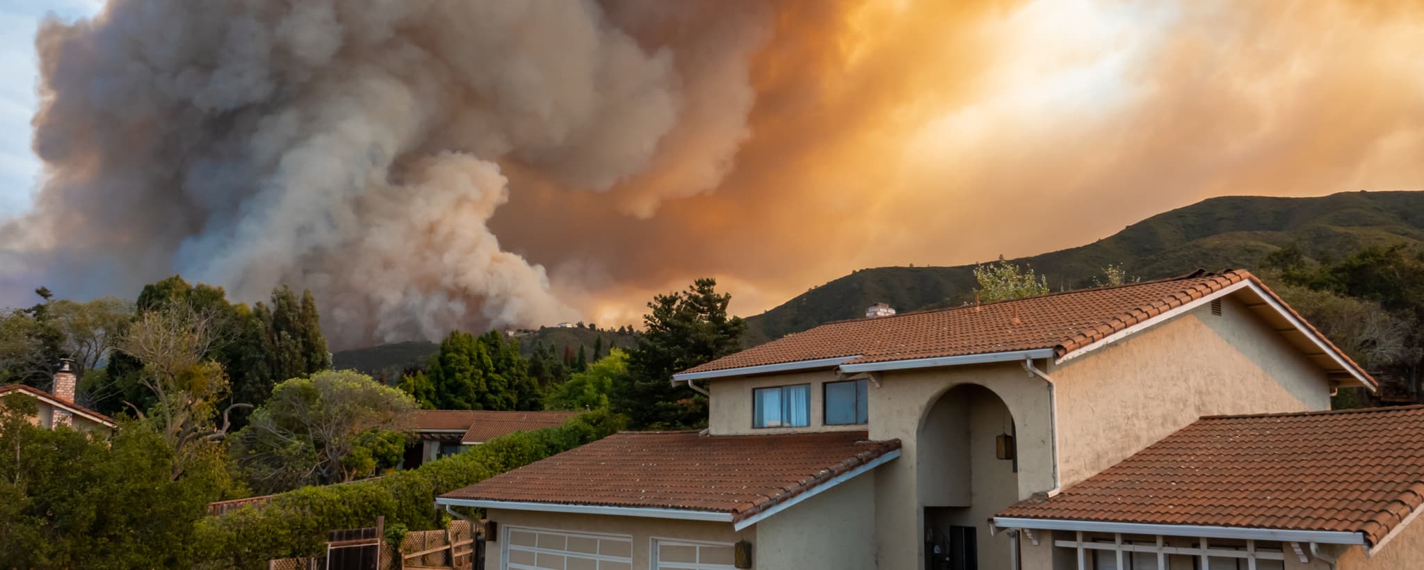House surrounded by wildfire smoke and orange haze, illustrating the need for air purification during wildfires